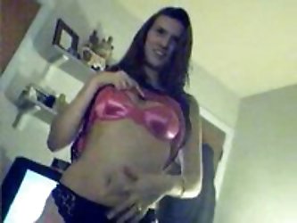 Tall girl in satin pink corset and tiny black panties poses for sexy vid shots and touches her bare pussy for the camera. She has a matching pink bra