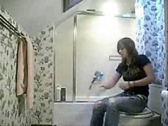 girl gets changed in bathroom in front of camera hidden by her friend. Strips off her clothes and has a bath before noticing a hidden camera placed at